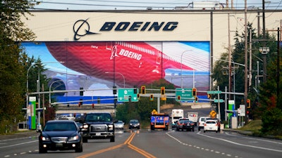 Traffic passes in view of a massive Boeing airplane production plant.