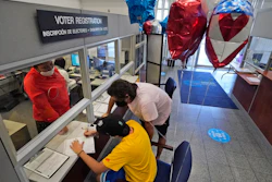 Lucas Saez, 22, fills out his voter registration form as his father Ramiro Saez looks on at the Miami-Dade County Elections Department, Doral, Fla., Oct. 6, 2020.