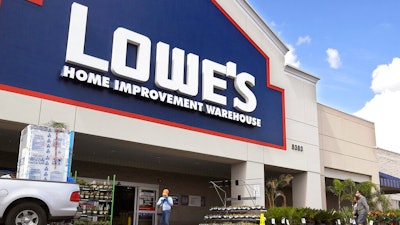 Customers wearing masks walk into a Lowe's home improvement store.
