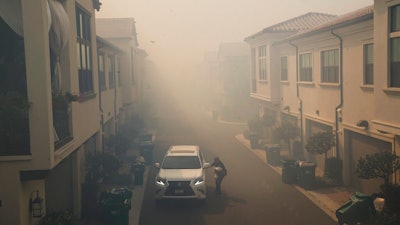 A man leaves his home during a mandatory fire evacuate as smoke from the Silverado Fire fills the air, Monday, Oct. 26, 2020, in Irvine, Calif.