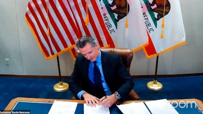 In this Wednesday, Sept. 30, 2020 file image made from video from the Office of the Governor, California Gov. Gavin Newsom signs into law a bill that establishes a task force to come up with recommendations on how to give reparations to Black Americans in Sacramento, Calif. A conservative legal group announced Monday, Oct. 5 that it sued to block California's first-in-the-nation law that requires hundreds of corporations based in the state to have directors from racial or sexual minorities on their boards.