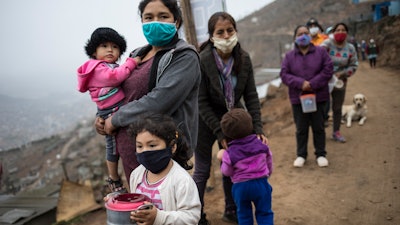 People line up for a free meal in the Villa Maria del Triunfo district in Lima, Peru, June 17, 2020.