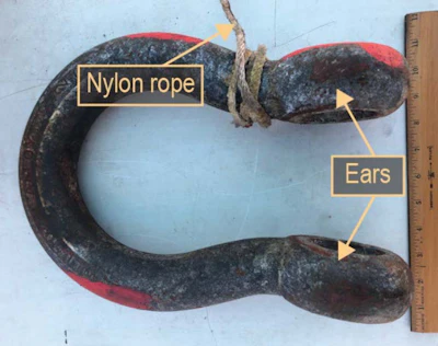 Recovered 50-ton shackle with nylon rope, bent ear, and missing pin.