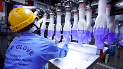 A worker inspects disposable gloves at the Top Glove factory in Shah Alam on the outskirts of Kuala Lumpur, Malaysia.