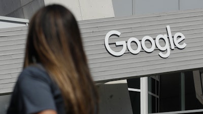 In this Sept. 24, 2019, file photo a woman walks below a Google sign on the campus in Mountain View, Calif. In the years since Barack Obama and Joe Biden left the White House, the tech industry's political fortunes have flipped. Facebook, Google, Amazon and Apple have come under scrutiny from Congress, federal regulators, state attorneys general and European authorities.