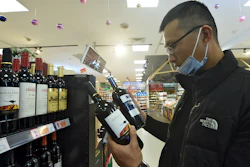 A man wearing a face mask compares two bottles of Australian wine at a supermarket in Hangzhou in east China's Zhejiang province on Nov. 27.
