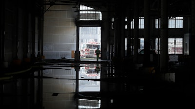 In this May 23, 2020 photo, a fire official is shown reflected in a puddle in a warehouse after a fire broke out before dawn on a pier at Fisherman's Wharf in San Francisco.
