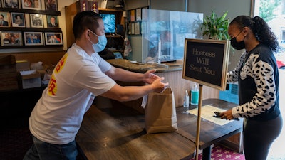 Benny Yun, owner of Yang Chow restaurant, left, delivers a take-out order in Los Angeles on Dec. 17.