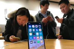In this Monday, Nov. 6, 2017, file photo, shoppers check out smart phones at a store in Beijing, China. Companies including the Chinese arm of TripAdvisor Inc. have been ordered by regulators to overhaul their mobile phone apps in what the Chinese government says is a crackdown on pornography and other improper content.