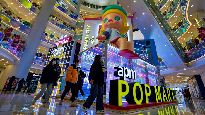 Shoppers wearing face masks to help curb the spread of the coronavirus wall by the Chinese toy maker POP Mart display booth at a shopping mall in Beijing on Dec. 9, 2020.