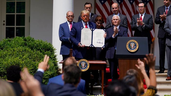 In this June 5, 2020 file photo, President Donald Trump poses for a photo after signing the Paycheck Protection Program Flexibility Act during a news conference in the Rose Garden of the White House in Washington. Thousands of minority-owned small businesses were at the end of the line in the government’s coronavirus relief program as many struggled to find banks to accept their applications. Or, they were disadvantaged by the program's terms. Data from the Paycheck Protection Program analyzed by The Associated Press show many minority owners desperate for a loan didn’t receive one until the PPP's last weeks.