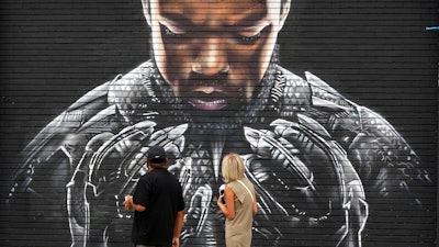 Pedestrians look up at a mural by artist Shane Grammer of late actor Chadwick Boseman's character T'Challa from the 2018 film 'Black Panther,' on Sept. 8, 2020, in Los Angeles.