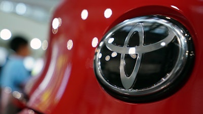 In this Aug. 2, 2019, file photo, people walk by the logo of Toyota at a show room in Tokyo.