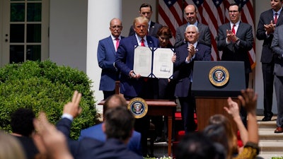 In this June 5, 2020 file photo, President Donald Trump poses for a photo after signing the Paycheck Protection Program Flexibility Act during a news conference in the Rose Garden of the White House in Washington. Thousands of minority-owned small businesses were at the end of the line in the government’s coronavirus relief program as many struggled to find banks to accept their applications. Or, they were disadvantaged by the program's terms. Data from the Paycheck Protection Program analyzed by The Associated Press show many minority owners desperate for a loan didn’t receive one until the PPP's last weeks.