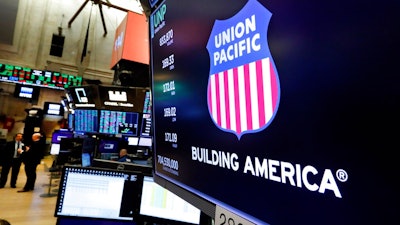 In this Sept. 13, 2019, file photo the logo for Union Pacific appears above a trading post on the floor of the New York Stock Exchange. Union Pacific’s fourth quarter profit chugged ahead as shipping volume improved for the first time since before the coronavirus pandemic slowed the economy to a crawl last year. The Omaha, Nebraska-based railroad said Thursday, Jan. 21, 2021, that it earned $1.38 billion, or $2.05 per share, in the quarter, but the results were weighed down by a one-time charge of $278 million.