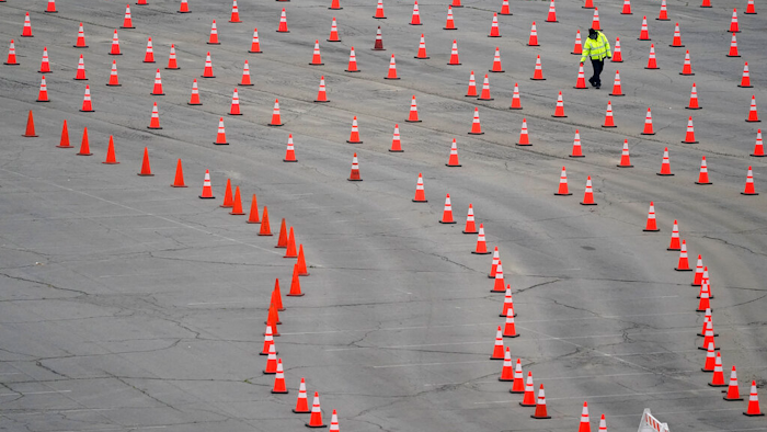 A worker arranges cones at a mostly-empty vaccination site at Dodger Stadium, Los Angeles, Feb. 11, 2021.