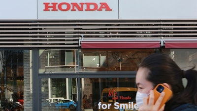 A woman wearing a face mask walks in front of a Honda Motor Co. showroom in Tokyo.