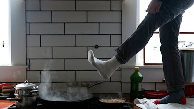 Jorge Sanhueza-Lyon stands on his kitchen counter to warm his feet over his gas stove Tuesday, Feb. 16, 2021, in Austin, Texas. Power was out for thousands of central Texas residents after temperatures dropped into the single digits when a snow storm hit the area on Sunday night.