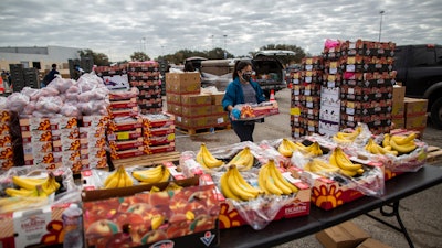 In this file photo, a volunteer carries food to be distributed during the Neighborhood Super Site food distribution event organized by the Houston Food Bank and HISD, in Houston.