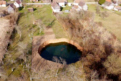 This aerial photo shows a sinkhole in the village of Mececani, central Croatia, Thursday, March 4, 2021. A central Croatian region about 40 kilometers (25 miles) southwest of the capital Zagreb is pocked with round holes of all sizes, which appeared after December's 6.4-magnitude quake that killed seven people and caused widespread destruction. Scientists have been flocking to Mecencani and other villages in the sparsely-inhabited region for observation and study.