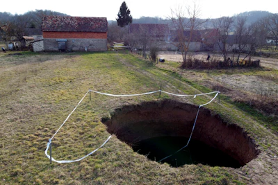 This aerial photo shows a sinkhole in the village of Mececani, central Croatia, Thursday, March 4, 2021. A central Croatian region about 40 kilometers (25 miles) southwest of the capital Zagreb is pocked with round holes of all sizes, which appeared after December's 6.4-magnitude quake that killed seven people and caused widespread destruction. Scientists have been flocking to Mecencani and other villages in the sparsely-inhabited region for observation and study.