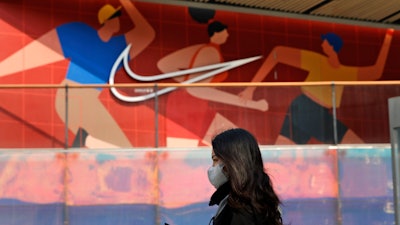 A woman wearing a mask passes by a Nike store in Beijing on Thursday, March 25, 2021. China's ruling Communist Party is lashing out at H&M and other clothing and footwear brands as it retaliates for Western sanctions imposed on Chinese officials accused of human rights abuses in the northwestern region of Xinjiang.