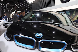 In this file photo, a worker cleans an electric vehicle at the BMW booth during the Auto Shanghai show.