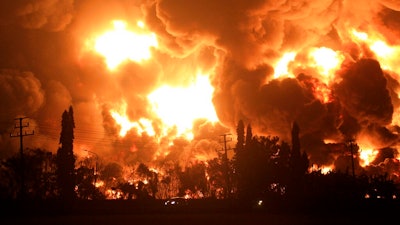 Cars pass by as fire razes through Pertamina Balongan Refinery in Indramayu, West Java, Indonesia, early Monday, March 29, 2021. Hundreds of people were evacuated from a nearby village after the massive fire broke out at the refinery.