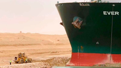 In this photo released by the Suez Canal Authority, a cargo ship, named the Ever Green, sits with its bow stuck into the wall.
