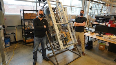 Purdue University researchers Eckhard Groll (left) and Leon Brendel stand next to a fridge experiment they designed to work in different orientations - even upside down.