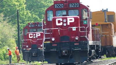 In this May 23, 2012 file photo, surveyors work next to Canadian Pacific Rail trains which are parked on the train tracks in Toronto.