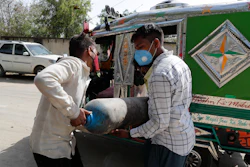 People carry a medical oxygen cylinder at a charging station on the outskirts of Prayagraj, India, Friday, April 23, 2021. India put oxygen tankers on special express trains as major hospitals in New Delhi on Friday begged on social media for more supplies to save COVID-19 patients who are struggling to breathe. India's underfunded health system is tattering as the world's worst coronavirus surge wears out the nation, which set another global record in daily infections for a second straight day with 332,730.