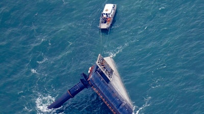 A rescue boat is seen next to the capsized lift boat Seacor Power seven miles off the coast of Louisiana in the Gulf of Mexico Sunday, April 18, 2021. The vessel capsized during a storm on Tuesday.