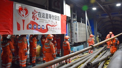 In this photo released by Xinhua News Agency, rescue workers stand near a banner which reads: 'Home is waiting for your region' at the entrance to a flooded coal mine.
