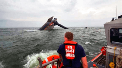 In this photo provided by the U.S. Coast Guard, A Coast Guard Station Grand Isle 45-foot Response Boat-medium boat crew member searches for survivors near the capsized SeaCor Power. The Seacor Power, an oil industry vessel, flipped over Tuesday, April 13, 2021 in a microburst of dangerous wind and high seas.