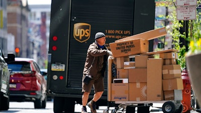 A UPS driver delivers packages in Philadelphia, Monday, April 26, 2021. A surge in the volume of deliveries that arrived with the start of the pandemic has not eased at UPS, where consolidated average daily volume jumped 14.3% in the first quarter. The Atlanta company on Tuesday, April 27 posted earnings of $4.79 billion, or $5.47 per share.