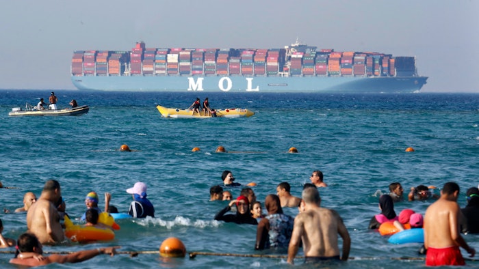 Beachgoers near Cairo watch a massive container ship sail to the Red Sea.