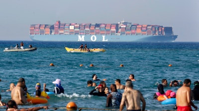 Beachgoers near Cairo watch a massive container ship sail to the Red Sea.