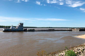 A tugboat with a barge attached sits near a boat ramp at Meeman-Shelby Forest State Park, Wednesday, May 12, 2021, in Millington, Tenn. A crack in the Interstate 40 bridge linking Tennessee and Arkansas has shut down Mississippi River traffic near Memphis, forcing tugs that are hauling barges to wait until they receive clearance that it's safe to pass under the closed bridge.