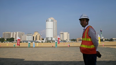 A construction worker stands on land that was reclaimed from the Indian Ocean for the Colombo Port City project, Colombo, Sri Lanka, Jan. 2, 2018.