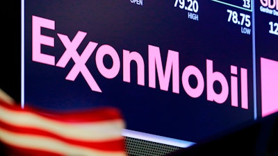 In this April 23, 2018, file photo, the logo for ExxonMobil appears above a trading post on the floor of the New York Stock Exchange. Exxon Mobil is facing a major challenge from a group of investors in one of the biggest fights a corporate boardroom has faced over its stance on climate change, an issue of rising urgency among many shareholders. The investor group is pushing to replace four of the oil giant’s board members with executives who they say are better suited to make money and to lead the company through a transition to cleaner energy.