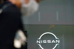 A man wearing a face mask to to help curb the spread of the coronavirus walks by the logo of Nissan seen at the automaker's showroom in Tokyo Tuesday, May 11, 2021. Nissan reduced its losses for January-March, compared to last year, as restructuring efforts kicked in, despite the sales damage from the coronavirus pandemic, the Japanese automaker said Tuesday.