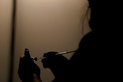A volunteer vaccinator prepares to administer a dose of the Pfizer coronavirus vaccine at a vaccine centre in the Swaminarayan School in Neasden, north London, Saturday, May 1, 2021.