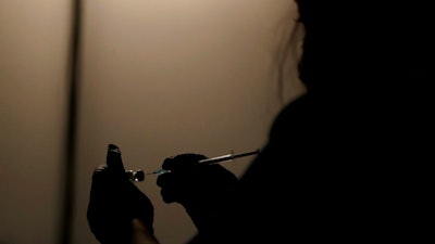 A volunteer vaccinator prepares to administer a dose of the Pfizer coronavirus vaccine at a vaccine centre in the Swaminarayan School in Neasden, north London, Saturday, May 1, 2021.