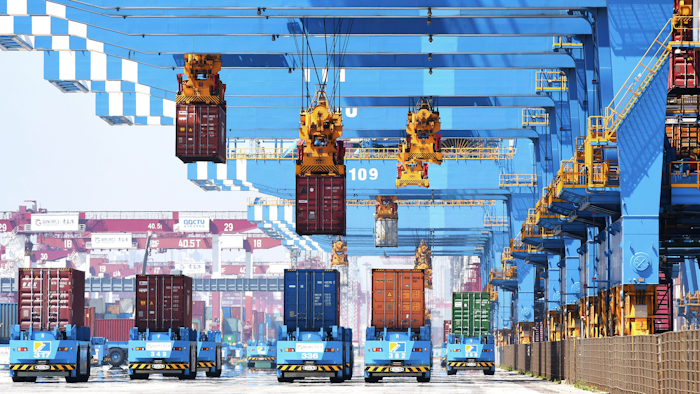 Gantry cranes move containers onto transporters at a port in Qingdao, China, June 4, 2021.