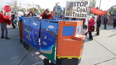 In this Oct. 17, 2013, file photo, a protester rides in a mock coal train as other protesters demonstrate against trains carrying coal for export moving through Washington state in Tacoma, Wash.