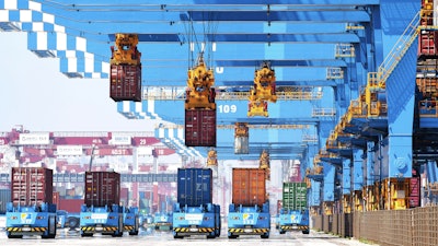 Gantry cranes move containers onto transporters at a port in Qingdao, China, June 4, 2021.