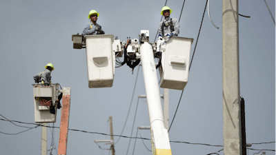 In this Oct. 19, 2017 file photo, Puerto Rico Electric Power Authority workers repair distribution lines damaged by Hurricane Maria in the Cantera community of San Juan, Puerto Rico. Luma, the private company that took over power transmission and distribution in June 2021 has struggled with widespread outages, affecting more than 1 million customers so far in its first two weeks.