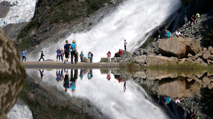 In this July 31, 2013, file photo, tourists visiting the Mendenhall Glacier in the Tongass National Forest are reflected in a pool of water as they make their way to Nugget Falls in Juneau, Alaska. The Biden administration said Thursday, July 15, 2021, that it is ending large-scale, old-growth timber sales on the nation's largest national forest.