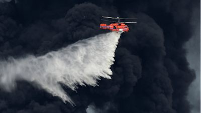 A helicopter drops a fire-retardant in a massive factory fire in Samut Prakan province, Thailand, Monday, July 5, 2021. A massive explosion at a factory on the outskirts of Bangkok has shaken an airport terminal serving Thailand’s capital, damaged homes in the surrounding neighborhood, and prompted the evacuation of a wide area over fears of poisonous fumes from burning chemicals and the possibility of additional denotations.